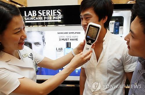 Men receive skincare counseling at a department store cosmetics counter. (Yonhap News)