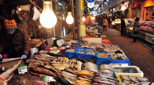 A merchant works on a fish at an almost empty traditional market in Gwangjin-gu, eastern Seoul. (Kim Myung-sub/The Korea Herald)