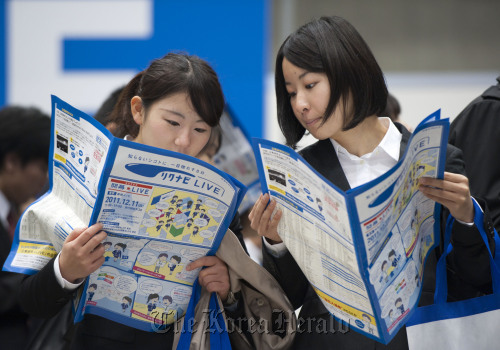 Job seekers study information booklets at a job fair hosted by Recruit Co. at Makuhari Messe in ChibaCity, Japan. (Bloomberg)