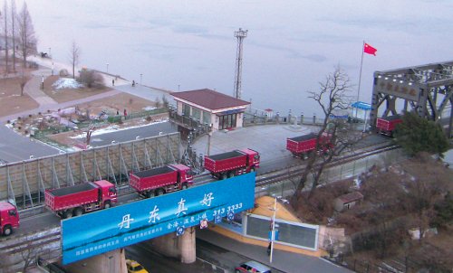 Cargo trucks cross a rail bridge over the Yalu River into North Korea from China’s border city of Dandong on Dec. 22. (Yonhap News)