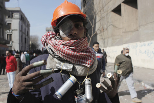 An Egyptian protester displays spent tear gas canisters and shotgun rounds during clashes with security forces near the Interior Ministry in Cairo, Egypt, Sunday, Feb. 5, 2012. Volleys of tear gas left a white cloud over Cairo's Tahrir Square and surrounding streets in the vicinity of Egypt's Interior Ministry, in the fourth day of clashes between security forces and rock-throwing youth protesting a deadly soccer riot. (AP)