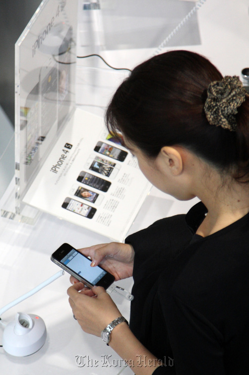 A customer tries an Apple Inc. iPhone 4S at a KDDI Corp. shop in Tokyo. (Bloomberg)