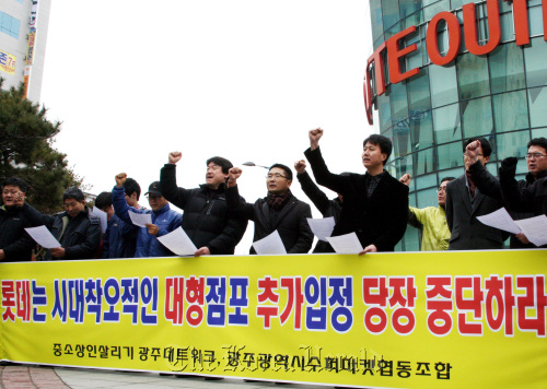 Members of groups representing small vendors and non-franchise supermarkets rally against the establishment of new discount stores in front of a Lotte Mart on Tuesday in Gwangju. (Yonhap News)