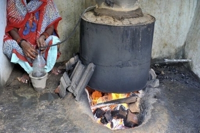 An Indian woman squats beside a still which is used to make a home-made liquor. (AFP)