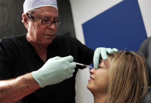 Dr Richard Ellenbogen injects botox into smile wrinkles on the bridge of Perla Pacheco's nose at Beverly Hills Body Cosmetic Surgery Specialists in Los Angeles (Bloomberg)