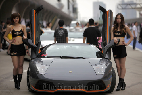 Models pose with a Lamborghini SpA sports car during the Shanghai International Circuit Club Challenge in Shanghai. (Bloomberg)