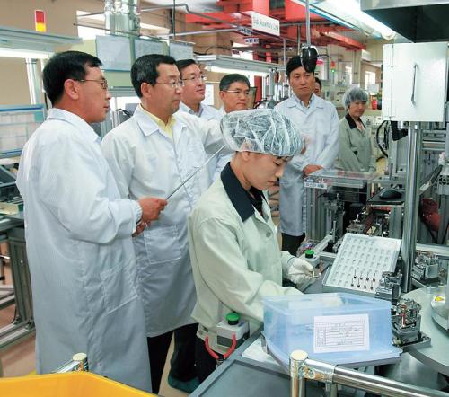 LS Group chairman John Koo (second from left) visits LS Industrial Systems’ electric car part production line in Cheonan, South Chungcheong Province. (LS Group)