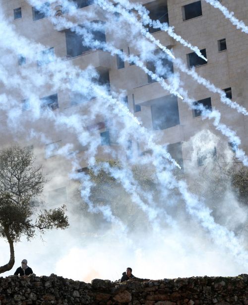 Palestinian protesters take cover as Israeli troops fire tear gas during a demonstration outside the entrance of Ofer Prison near Ramallah in West Bank. (AFP-Yonhap News)