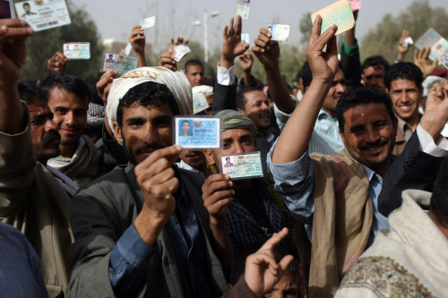 Yemeni men show their identity cards as they line-up outside a polling station to cast their votes in the presidential election in Sanaa on Tuesday. (UPI-Yonhap News)