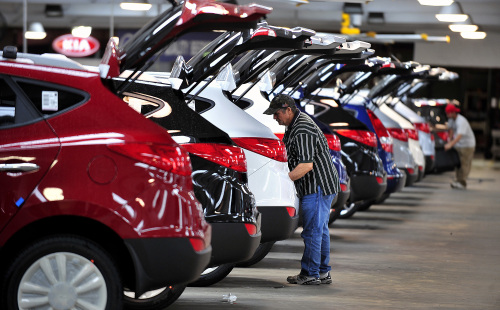 An employee installs a cargo mat on a Kia Motors Corp. Tucson sports utility vehicle at the International Auto Processing Inc. facility at Georgia Ports Authority Colonel’s Island auto import and export terminal in Brunswick, Georgia, U.S., Monday. (Bloomberg)