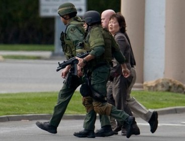 An unidentified woman identified by police as the hostage, is escorted by SWAT officers away from the Saehan Bank following gunfire that wounded the suspected hostage-taker. (AP photo)