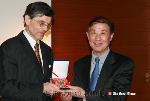 German Ambassador Hans-Ulrich Seidt presents a medal to press officer Doe Phil-young at a dinner held to mark his 40 years of service to the German Embassy on Monday. (Seoul Times)