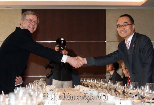 Finance Minister Bahk Jae-wan (right) shakes hands with EU Ambassador Thomas Kozlowski before having a luncheon meeting with ambassadors from EU member states in Seoul on Monday. (Yonhap News)