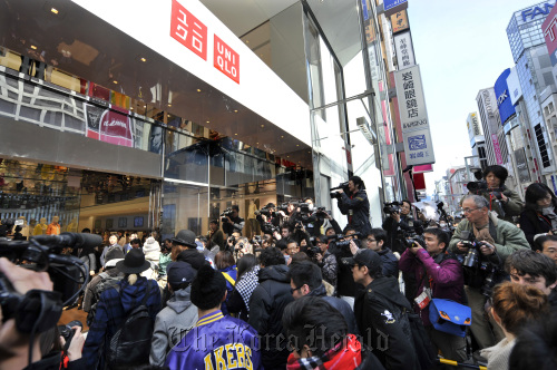 Members of the media crowd round the entrance as the first group of customers enter Fast Retailing Co.’s Uniqlo store in the Ginza district of Tokyo on Friday. (Bloomberg)