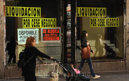 Pedestrians walk past a closed down store in Madrid. (Bloomberg)