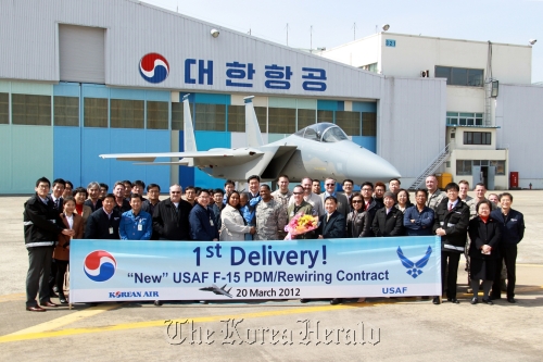 Officials of the U.S. Department of Defense and F-15 crew pose for a photo with Korean Air staff in front of the F-15 fighter rewired and repaired at the Korean Air Tech Center in Busan on Tuesday. (Korean Air)