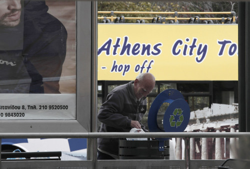 An elderly man searches in a garbage bin at the tram station in central Athens. (AP-Yonhap News)