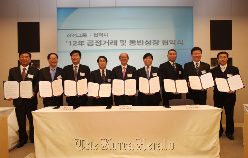 Participants of the fair trade and mutual growth event organized by Samsung and its affiliates hold up their signed treaties at Samsung’s office in southern Seoul on Thursday. (Samsung Electronics)