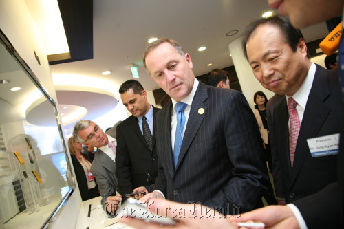 New Zealand Prime Minister John Key (second from right) and Samsung Electronics’ mobile chief Shin Jong-kyun (right) view the features of the Korean IT giant’s gadget Galaxy Note at the firm’s digital complex in Suwon, Gyeonggi Province on Monday.(Samsung Electronics)