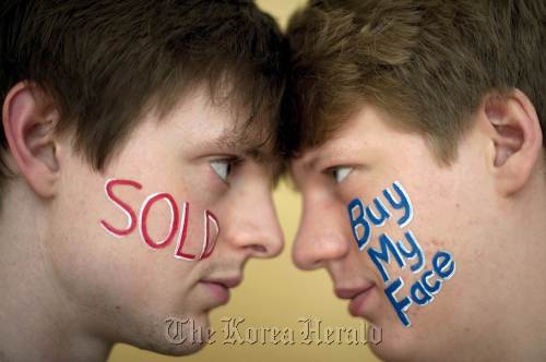 Buymyface.com founders Ross Harper (right) and Ed Moyse pose for photographs in London on March 23. (AFP-Yonhap News)