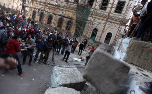 Egyptian protesters break a concrete block wall erected by security forces to separate the prime minister’s headquarters and Tahrir Square in Cairo on Friday. (AP-Yonhap News)