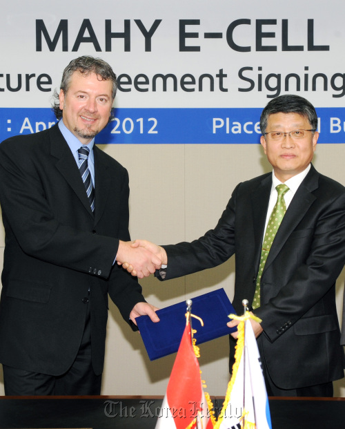 Hyundai Heavy Industries’ senior executive vice president of green energy Lee Choong-dong (right) and Magna E-Car Systems’ chief financial officer John Simonetti shake hands after signing an agreement to form a joint venture for electric car batteries at the shipbuilder’s Seoul office on Monday. (HHI)
