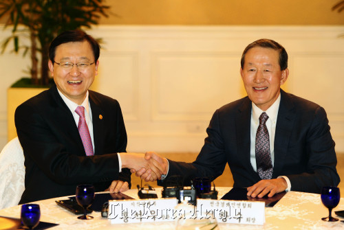 Knowledge Economy Minister Hong Suk-woo (left) shakes hands with FKI chief Huh Chang-soo during their meeting at a Seoul hotel on Tuesday. (MKE)