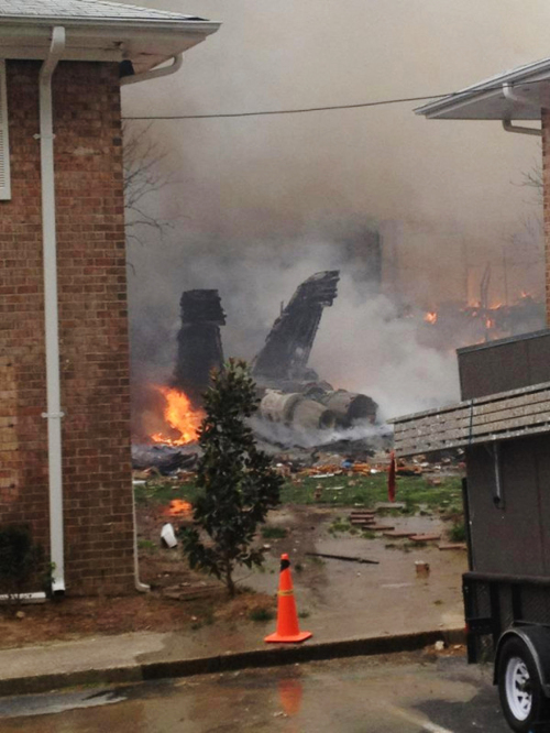 The burning fuselage of an F/A-18 Hornet lies smoldering after crashing into a residential building in Virginia on Friday. (AP-Yonhap News)