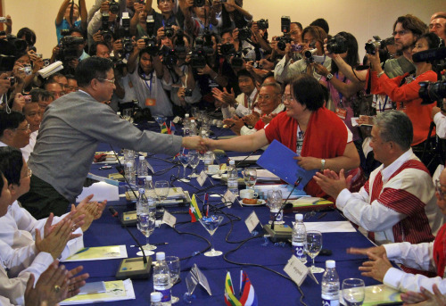 Myanmar’s Railway Minister and head of the government negotiation group Aung Min (left), shakes hands with Naw Si Pho Ra Sein, general secretary of the Karen National Union, during their peace building meeting at a hotel in Yangon. (AP-Yonhap News)