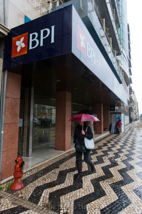 A pedestrian passes the window of a Banco BPI SA branch in Lisbon. (Bloomberg)