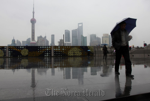 Pedestrians walk near the Huangpu River with the Lujiazui Financial District in the distance in Shanghai. (Bloomberg)