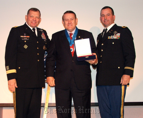 Ned Stoll (center) poses with USFK commander Gen. James D. Thurman (left), and Yongsan garrison commander Col. William P. Huber after being announced the Area II Volunteer of the Year at a ceremony at U.S. Army Garrison Yongsan in Seoul on April 20. Staff Sgt. (Cody Harding)