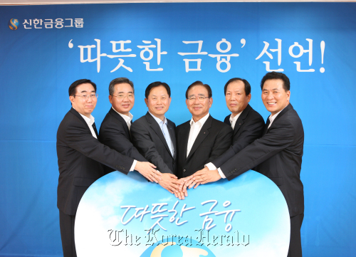 Shinhan Financial Group chairman Han Dong-woo (fourth from left) poses with business unit chiefs, including bank CEO Suh Jin-won (third from left), after unveiling the group’s business policy toward warm-hearted services. (Shinhan Financial)