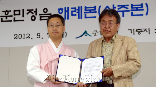 Kim Chan (left), administrator of the Cultural Heritage Administration, and Jo Yong-hun, who handed over his ownership of Hunminjeongeum Haeryebon Sangjubon to the agency, pose for a photo at the ceremony on Monday in Seoul. (Kim Myung-sub/The Korea Herald)
