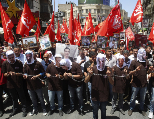 Palestinians wear hoods with printed faces of Palestinian prisoners on hunger strike in Israeli jails during a support rally in Nablus, West Bank, to demand better conditions in Israeli jails on Saturday. (AP-Yonhap News)