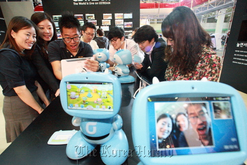 A group of people test the “kibot,” KT’s robot for kids, at the company’s exhibition booth during World IT Show 2012. (KT)