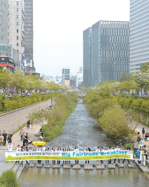 People hold up a banner to celebrate the Big Fairtrade Breakfast on Seoul’s Cheonggyecheon on May 12. (Fairtrade Marketing Organization Korea)