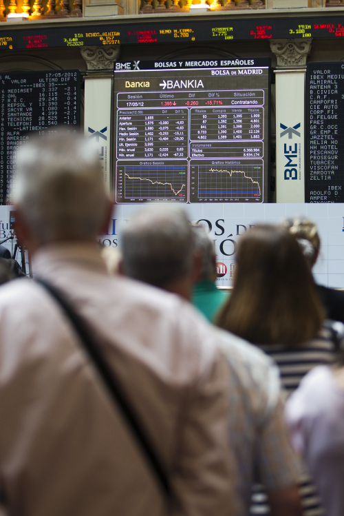 Visitors look at the share price information for Bankia SA inside the Bolsas y Mercados stock exchange in Madrid on Thursday. (Bloomberg)