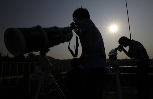 South Korean astronomy students use telescopes to observe a solar eclipse in Seoul, South Korea, Monday. (AP-Yonhap News)