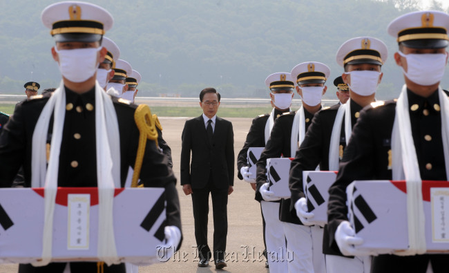 President Lee Myung-bak walks behind the honor guard carrying the remains of the 12 South Korean soldiers that arrived in Korea at the military airport in Seongnam, Gyeonggi Province on Friday. (Chung Hee-cho/The Korea Herald)