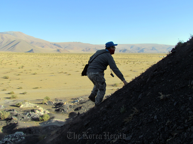 A mine researcher climbs a hill during mine hazards investigation. (KOICA)