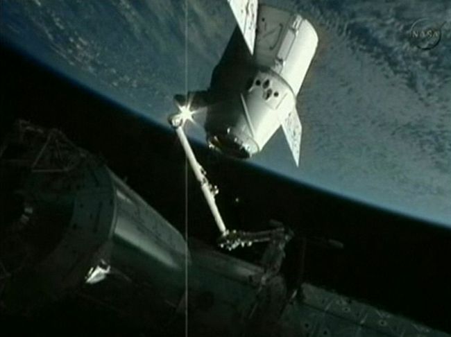 The robotic arm of the International Space Station holds the SpaceX Dragon capsule as astronauts prepare to dock the capsule with the station on Friday. (AFP-Yonhap News)