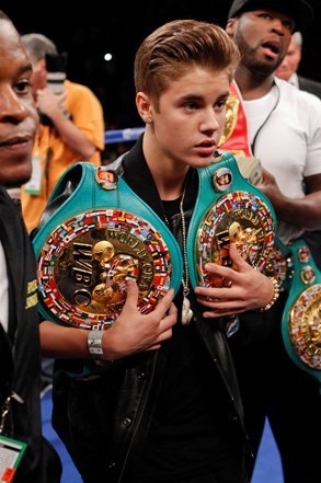 Justin Bieber carries Floyd Mayweather Jr.'s title belts into the ring, May 5, 2012, in Las Vegas. (AP)