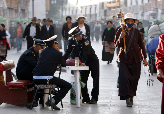 Security guards keep watch over Buddhist pilgrims as they walk on the Barkhor, the circular route around the Jokhang Temple in Lhasa, the capital of Tibet. (AP-Yonhap News)