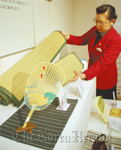 A saleswoman shows a fan and cooling straw mats at the Mitsukoshi Nihonbashi main store in Chuo Ward, Tokyo.  (Yomiuri Shimbun)