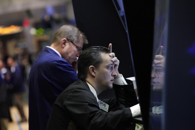 Trader Theodore Nelson (right) is reflected on a panel as he works on the floor of the New York Stock Exchange on Monday.