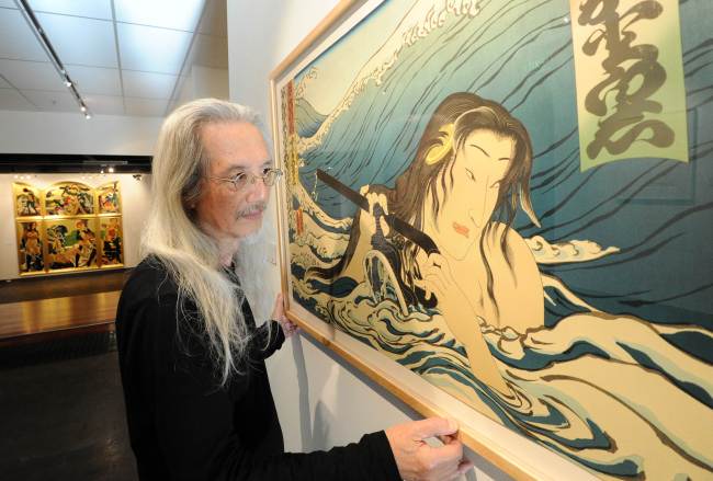 This photo taken on May 25 shows Japanese-born artist Masami Teraoka, age 78, as he straightens his painting entitled “Namiyo at Hanauma Bay 1985” at his exhibition in Sydney. (AFP-Yonhap News)