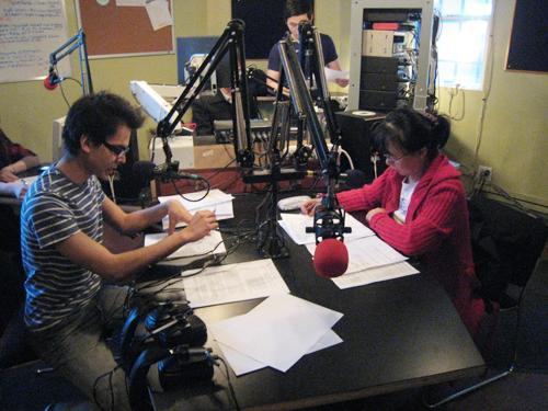 Voice of Korea’s English-language host Ravi Kalsi (left) and Korean host Dianna Chon reading their scripts during a live broadcast. (Yonhap News)