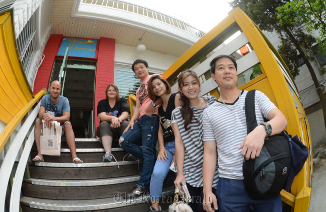 Travelers pose at Y3llow Submarine guesthouse in Hongdae before they take a tour around Seoul on Friday. (Chung Hee-cho/The Korea Herald)