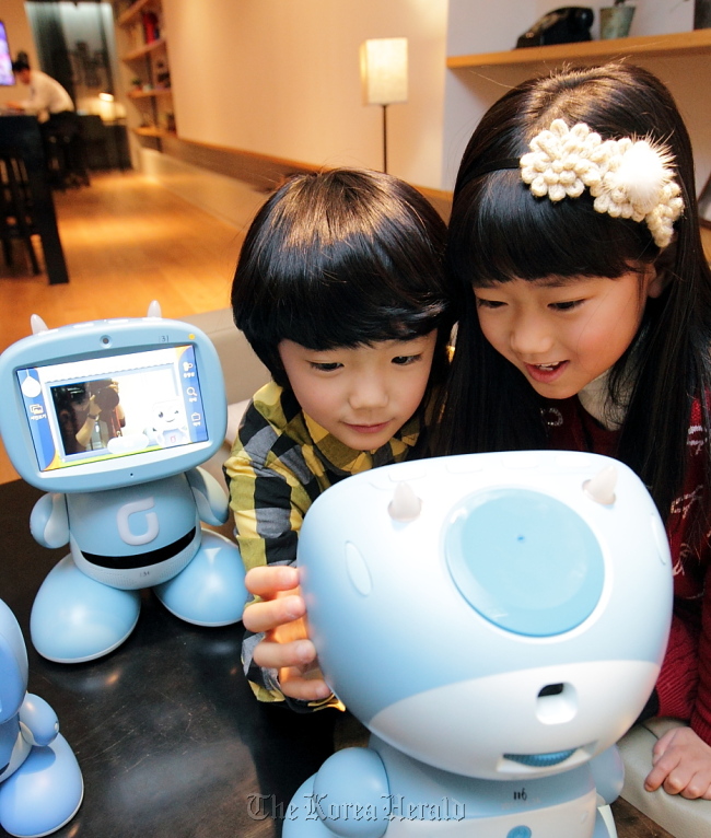 Children play and learn with the second-generation “Kibot,” a robot for kids introduced by KT, in Seoul on Wednesday. (KT)